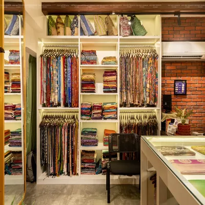 The display system is the heart of this boutique. I designed custom, brightly lit shelving and hanging racks to present the vibrant colors and textures of the saris, making the collection itself the primary design element.