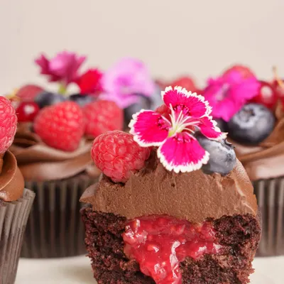 A close-up of the cross-section of my Dark Chocolate Berry Cupcake. You can see the rich chocolate cake, the gooey house-made raspberry compote filling, and the fresh berry topping.
