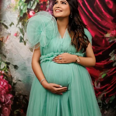 A moment of quiet reflection and anticipation. This expecting mother looks absolutely radiant in a delicate mint green tulle gown. The elegant pose, with her hands cradling her baby bump, beautifully highlights the bond between mother and child before they even meet.