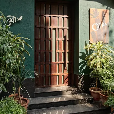 The entrance to Otra restaurant in Mumbai's historic Kala Ghoda district. The deep green facade and custom-designed wooden door create an intriguing first impression, hinting at the unique dining experience that lies within.