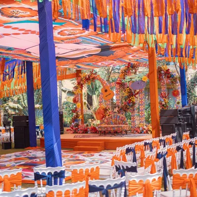 A full view of our Mexican-themed Mehendi setup. The vibrant decor includes a custom printed canopy, colorful tassel draping, and a floral-adorned stage, creating a lively fiesta atmosphere.