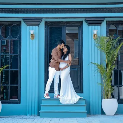 A stylish outdoor couple's maternity shoot. The modern architecture with its bold blue color provides a unique and vibrant backdrop for this intimate portrait.