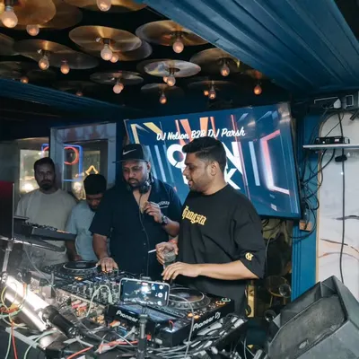 In discussion with DJ Nelson during our back to back set. We're coordinating the next sequence of tracks to keep the energy building.