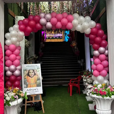 A beautiful pink and white balloon arch creating a grand entrance for a birthday party, complete with a personalized welcome sign.