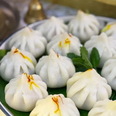 A close up of my classic Ukdiche Modaks, served on a traditional banana leaf. Each one is pleated by hand and garnished with precious saffron strands, just how my Aaji used to make them.
