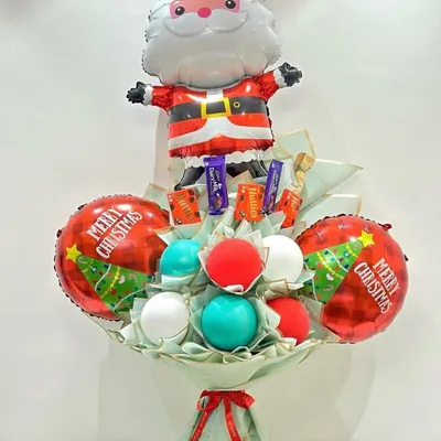 A festive Christmas-themed bouquet featuring a Santa Claus foil balloon, red and green accent balloons, and a selection of chocolates.