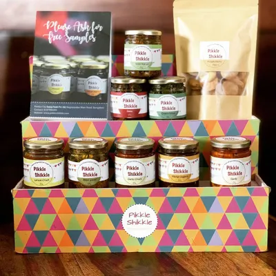 A complete view of our product range, featuring our colourful gift box. You can see our selection of pickles, jams, and a packet of our traditional Punjabi Mathri, perfect for gifting or stocking your pantry.