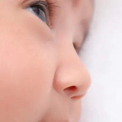 A macro shot of a newborn's profile, focusing on their bright, curious eye and tiny button nose. These are the details you will want to gaze at for years to come.
