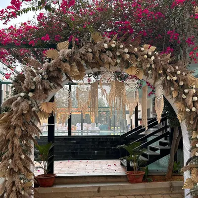 A beautiful boho-chic entrance arch. We used an abundance of dried pampas grass, palm leaves, and macrame hangings to create a dreamy, textured welcome for guests.