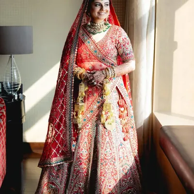 A full view of a classic red bridal lehenga, rich with embroidery. I help you achieve this iconic wedding look with my premium rental collection.