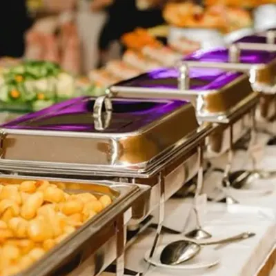 A close-up of a professionally arranged buffet line. I ensure the catering setup is clean, elegant, and inviting, with a variety of dishes served in high-quality chafing dishes to keep the food warm and fresh.