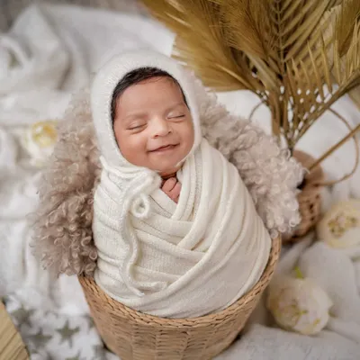A smile that warms the heart. I love this boho-inspired setup, using a wicker basket, a soft knitted bonnet, and dried palms for a natural, earthy feel.