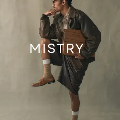 A campaign shot from one of our earlier collections, featuring our classic tan loafers and a structured leather briefcase. This image reflects our commitment to timeless style and quality craftsmanship.