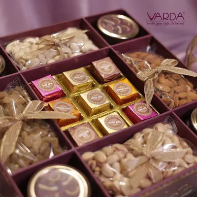 A close-up of a luxury gift hamper, showcasing an assortment of premium dry fruits and foil-wrapped chocolates. Each compartment is carefully arranged to create a visually appealing and delicious gift.