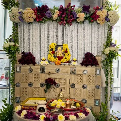 I designed this serene pooja corner for a client's home. The setup features a backdrop of delicate white rajnigandha strings, complemented by a lush arrangement of cream roses and deep purple flowers on a rustic wooden cabinet.