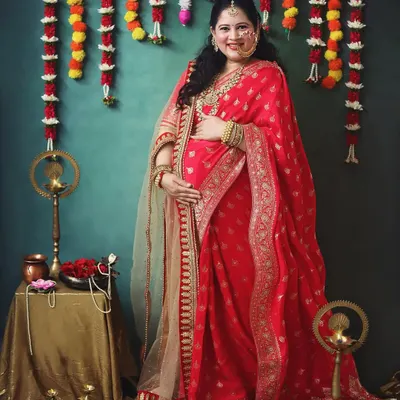 A portrait of a mother-to-be, glowing with happiness and tradition. The combination of the red banarasi saree and the soft dupatta creates such an elegant look for a pregnancy photoshoot.