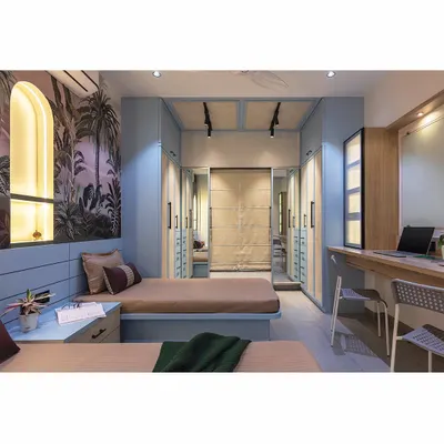 A dream room for teenage siblings. We used a sophisticated tropical wallpaper and a cool blue color palette to create a space that feels both youthful and grown-up. The design includes twin beds and a central shared study area.