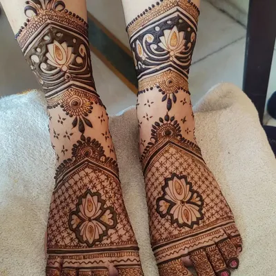 A stunning and clean bridal foot mehandi design. The combination of lotus figures with intricate net patterns creates a very elegant and traditional look.