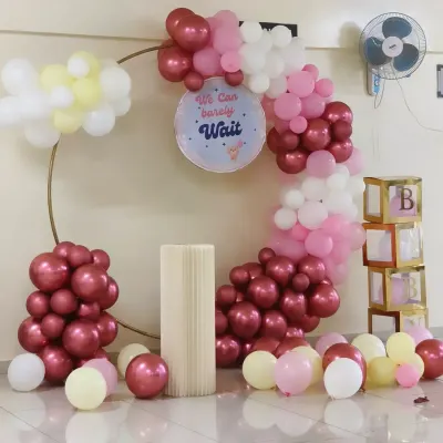"We can barely wait!" This stylish ring balloon decoration in shades of pink, white, and chrome was the perfect backdrop for a modern baby shower. The transparent boxes spelling "BABY" add a trendy touch.