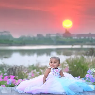 This outdoor portrait was taken during the magical golden hour. The warm sunset over the lake creates a stunning, colourful backdrop for this little girl in her beautiful pastel dress.