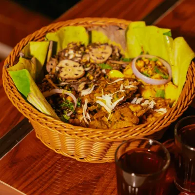 A Manipuri relish munch basket, featuring a mix of Singju, Bora, Kelichana, and Aloo mixture, served with red tea (Cha-ngang).