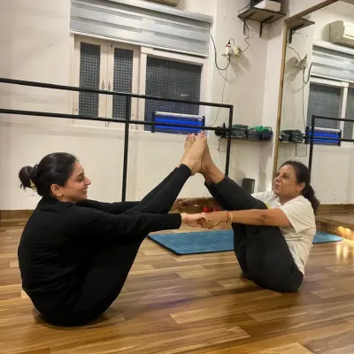 Partner yoga is a beautiful way to connect. Here, two students practice a partner boat pose (Navasana), relying on each other for balance and support.