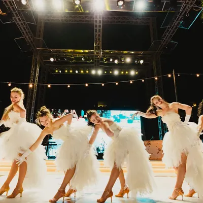 A troupe of dancers in elegant white tulle dresses, performing a choreographed routine. We work with top dance groups to add grace and energy to our events.