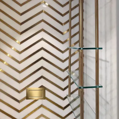 A detail shot from a luxury powder room I designed. The combination of white marble with a custom brass inlay in a chevron pattern creates a dramatic and sophisticated feature wall.