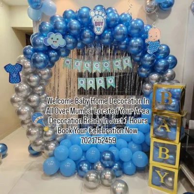 This popular 'Welcome Baby' setup for a boy features a full balloon arch in metallic blue and silver, a shimmering curtain backdrop, and transparent 'BABY' boxes filled with matching balloons. It's a complete package for a memorable welcome.