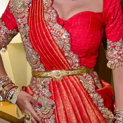 A close-up of a unique red bridal drape. This fusion style combines the look of a lehenga with the elegance of a saree, creating a modern and striking silhouette.