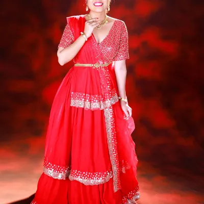 A vibrant, full-length portrait of a model in a stunning red lehenga. I used a textured red backdrop and specific lighting to create a rich, monochromatic look that makes the silver details pop.