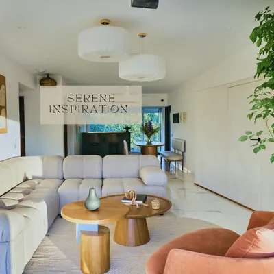 The open-plan living space in 'House on the Hill' is designed for serenity and flow. A plush, light-colored sectional sofa and nested wooden coffee tables create a comfortable gathering spot, all bathed in natural light.