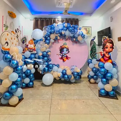 This Little Krishna theme was designed for a home celebration. It features a circular backdrop with Krishna artwork, a flowing organic balloon arch in shades of blue and white, and character cutouts of Krishna and a cow.