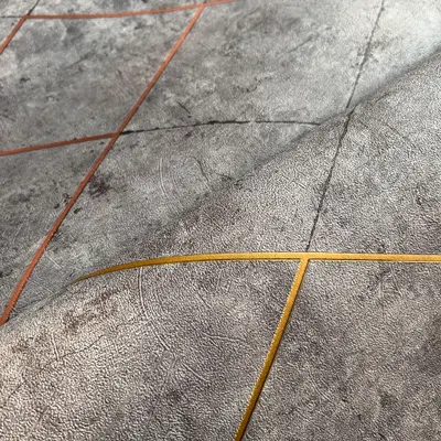 This modern geometric wallpaper features a textured grey background with intersecting lines in copper and gold. It's a luxurious design that adds a touch of contemporary elegance to any space.