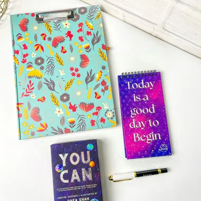 A styled flatlay of a floral clipboard, a 'You Can' card deck, and a motivational notepad. This composition is perfect for a stationery brand's social media or website.