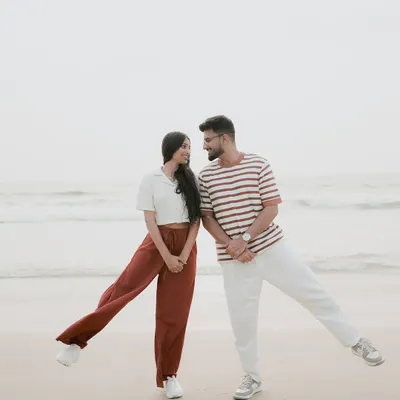 A fun, playful pose on the sands of a quiet beach. Coordinated casual outfits are a great choice for a relaxed and comfortable beach photoshoot.