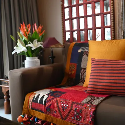 This scrap quilt, seen here on a sofa, is a celebration of asymmetry and spontaneity. It features a mix of machine and Boro-style hand stitching, with a vintage Kutch embroidery patch anchoring the composition.
