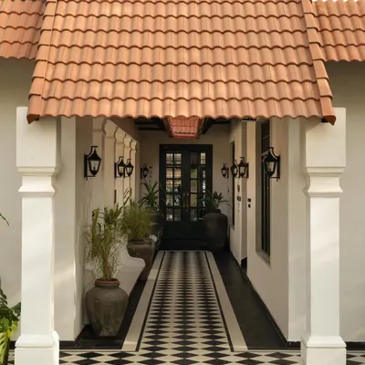The entrance to Elgin Cafe in Ludhiana, where a calibrated dialogue between colonial typology and contemporary clarity begins. The checkerboard path guides the eye, framed by classical columns and a terracotta roof.