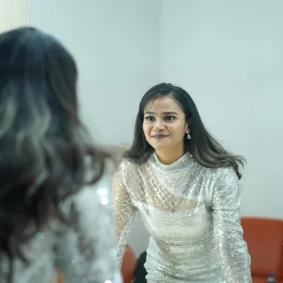 A behind-the-scenes moment, getting ready in a silver sequin dress. The mirror reflection adds depth and a sense of anticipation.