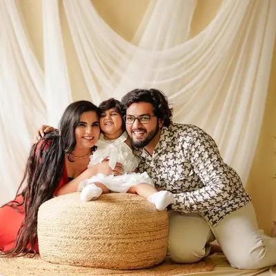 A happy family portrait from our boho studio set. The natural jute pouf, sheer curtains, and simple greenery create a warm and inviting atmosphere for capturing genuine smiles.