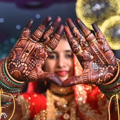 A beautiful bride framing her face with her hands, showcasing the rich, dark stain from my henna. I even included the couple's names, 'Saqlain' and 'Zoha', for a personal touch.