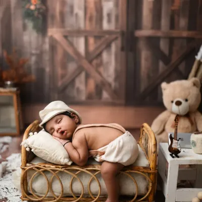 A little boy in a newsboy cap, sleeping peacefully on a miniature rattan bed. This rustic setup is full of charming, old-world details.