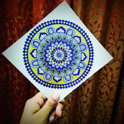 Here I am holding a finished mandala that uses a cool color palette of blue and green. It's amazing how colors can completely change the feeling of a design.