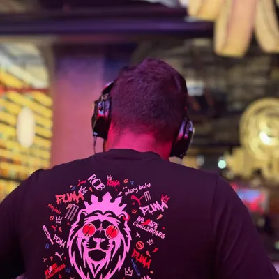 A view from behind the console during a set. This perspective shows the DJ at work, focused on the mix, with the vibrant club atmosphere in the background.