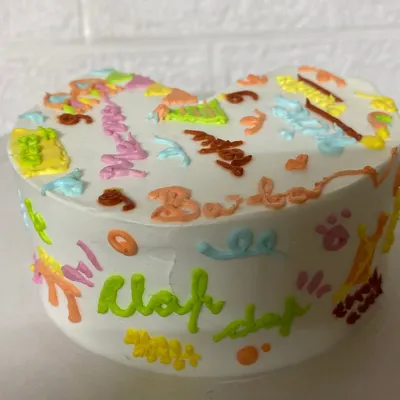 A side view of our doodle cake, covered in colourful, hand-piped illustrations that tell a unique story. This one celebrates 9 months of baby Mayan's favourites.