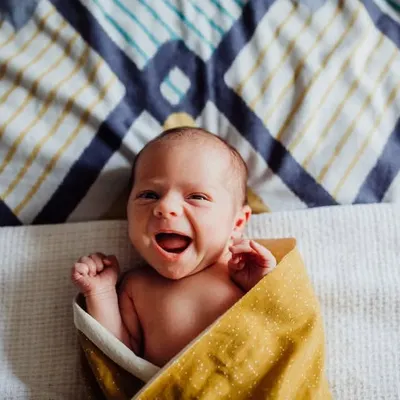 A beautiful, happy yawn from a newborn wrapped in a yellow blanket. We aim to capture these fleeting, expressive moments during our lifestyle newborn sessions.
