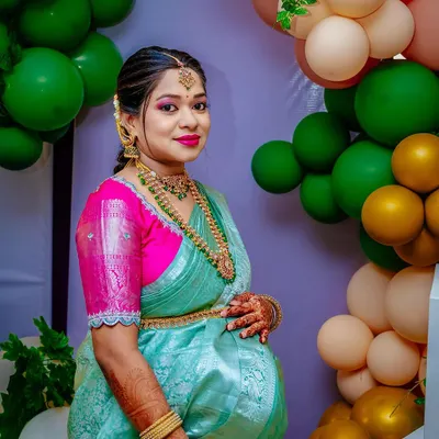 A close-up portrait of the radiant mother-to-be at her baby shower. Dressed in a beautiful traditional saree, she is glowing with happiness.