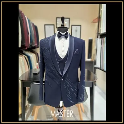 A three-piece navy blue tuxedo designed for a groom or groomsman. This suit features subtle, scattered embroidery on the jacket, adding a touch of sparkle to a classic silhouette.