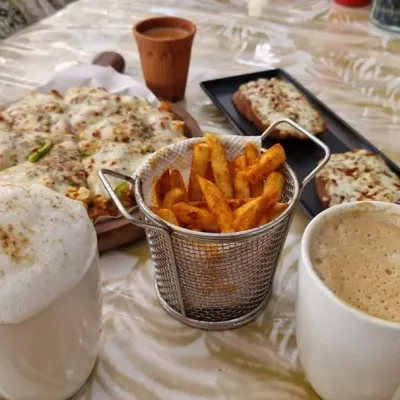 A perfect meal spread at My Baagaan. Cheesy pizza, crispy peri-peri fries, garlic bread, and frothy cappuccinos. It's comfort food at its best, enjoyed in the best atmosphere.