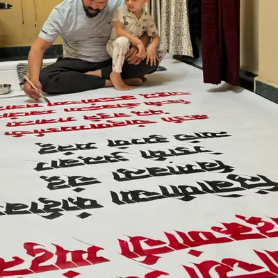 Working on a 15-foot long Marathi calligraphy paper roll for Gulmohar Day in Satara, with my son giving me company.